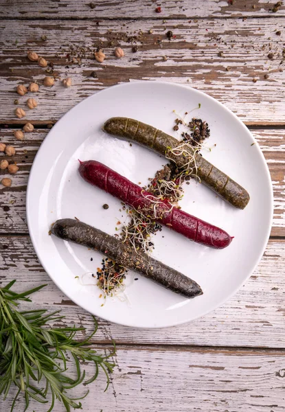 Plant based, meat free products. Grilled, roasted vegan, vegetarian sausages, top view. Rustic composition with spices and fresh herbs. Serving proposal, on a plate, on white vintage boards.