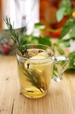 Biberiyeli bitki çayı, karanfil, zencefil, bal ve limon. Temiz bir cam fincanda sıcak erime, ahşap bir tezgahta bardak, masa. Sıcak, sağlıklı bitkisel içecek..