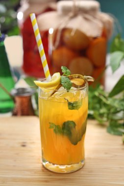 Bir bardak ferahlatıcı limonata, armutlu kokteyl, kekik, ahşap bir masada mango, tezgah. Çevre dostu kağıt kamışlı organik, vejetaryen bir içecek..
