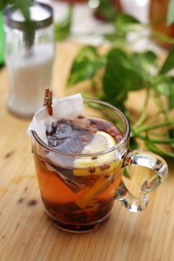 Tahta bir masada limonlu bir fincan meyve çayı, üst manzara. Sıcak, sağlıklı bitkisel içecek. Çay poşetiyle çay yapıyorum..