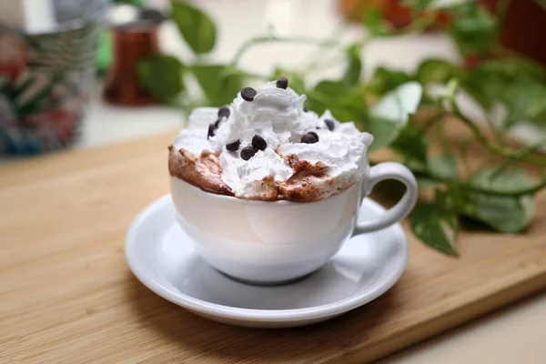 Café, capuchino, chocolate caliente con crema batida en un blanco, porcelana, taza de café, en una bandeja de madera. — Foto de Stock