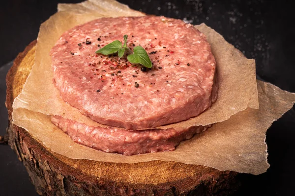 Сырое мясо, мясной рулет. Сырое мясо, французские стейки на бумаге, на дереворубке, на черном фоне. — стоковое фото