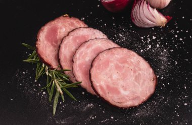 Dilimlenmiş krakowska sosisi, taze otlar ve siyah arka planda baharatlar, karatahta, karatahta. Polonya usulü.