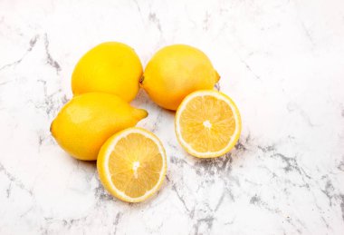Mermer arka planda birkaç sarı limon. Limon meyvesi, bütün ve yarım, yatay görüş. Olgun narenciye meyveleri.