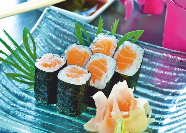 Sushi pronto. Salmone maki rotoli e zenzero sottaceto su un blu, piatto di vetro. Delicatezza giapponese. — Foto Stock