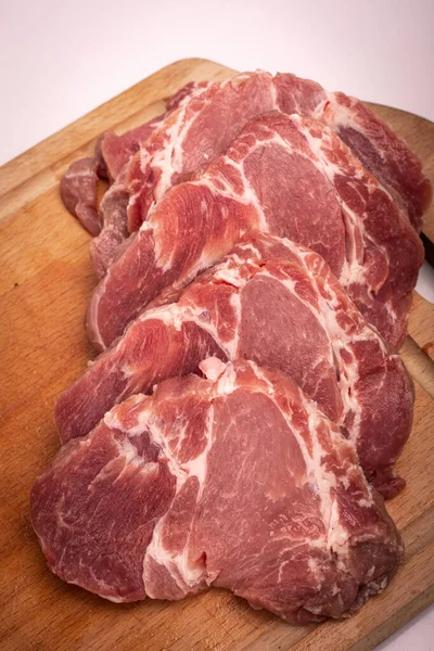 Domuz eti pirzolaya, dilimlere, tahta kesme tahtasına, beyaza kesilmiş. Çiğ domuz boyunlu biftek, pirzola, yakın plan.. — Stok fotoğraf