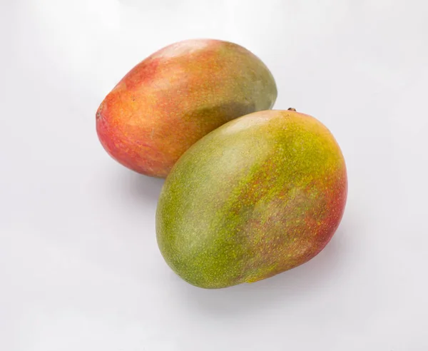 Twee hele mangovruchten, geïsoleerd. Rijp exotisch fruit op een witte achtergrond. Rechtenvrije Stockfoto's