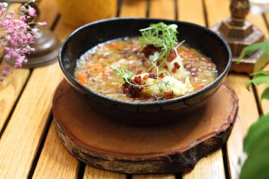 Lahana turşusu çorbasında hamur tatlısı, seçici odaklanma, yakın plan. Polonya pierogisiyle lahana çorbası. Ahşap bir masada, modern siyah bir kâsede. Restoranda öğle yemeği..
