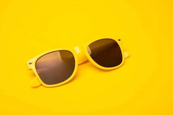 Yellow fancy, hipster sunglasses on a vibrant sunny background. Summertime, travel concept, banner, postcard with a copy space.