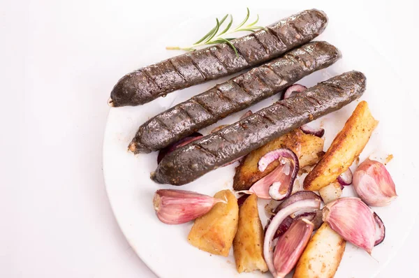 Grilled, roasted vegan, vegetarian sausages on a plate, isolated.. Composition with meat free products, buckwheat blood sausages, onion, garlic and spices, on a white background.