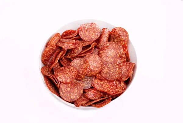 Salami chips, meat snacks in a bowl, isolated. Meat cold cuts, salami slices on a white background, top view. A packshot photo for package design, template.