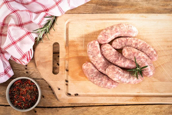 Traditional raw white sausage on a wooden cutting board. Rustic composition with Polish white sausage, spices and fresh rosemary. Easter delicacy.