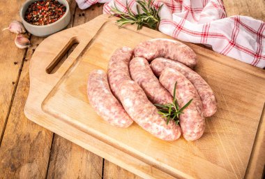 Traditional Polish raw white sausage on a wooden cutting board. Rustic composition with white sausage and fresh rosemary. Easter delicacy. 