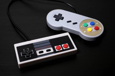 Siyah arka planda retrogamepad 'ler. Eski konsol kontrolörleri, video oyunları pedleri, yatay görüş. Klasik oyun aksesuarları. 