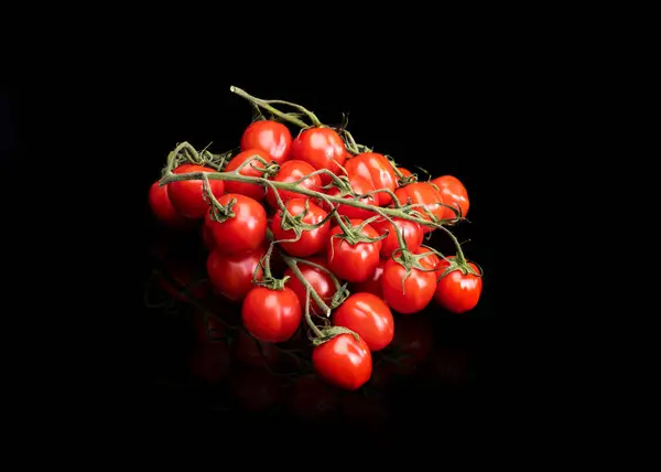 トップビューにチェリートマトを熟す 緑の小枝に小さな赤いトマトのグループ 黒の背景 — ストック写真