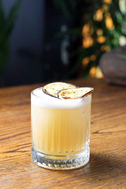 Kızarmış limon dilimleriyle süslenmiş köpüklü viski kokteyli. Klasik içki, viski, burbon, limon suyu, şeker ve yumurta beyazı, eski moda bir bardakta, ahşap bir masada..