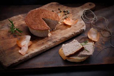 Ev yapımı, pişmiş et ezmesi. Yuvarlak ezmeli, ahşap kesme tahtasındaki, siyah arkaplanlı, kırsal bir kompozisyon..