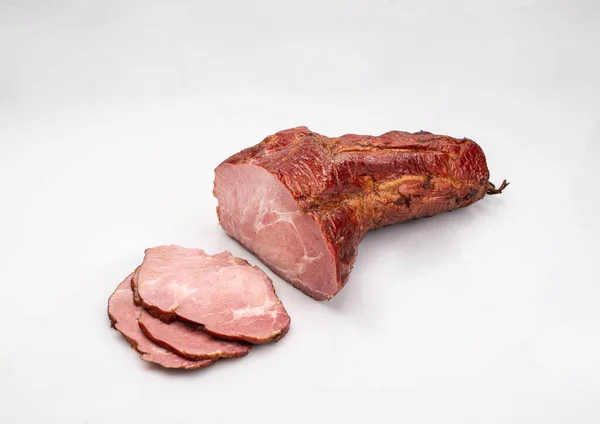 Gammon, smoked ham - in one piece and sliced, isolated on a white background. Homemade, Polish cold cuts, in netting. Traditional meat product, a packshot photo.