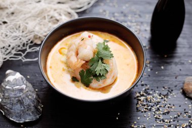 Kral karidesli Tayland Tom Kha çorbası. Siyah kase, doğu karides çorbası, siyah ahşap masa, üst manzara, seçici odak.