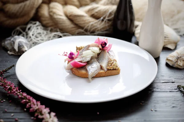 Sandwich Met Haring Gepekelde Versierd Met Eetbare Bloemen Een Witte Rechtenvrije Stockfoto's