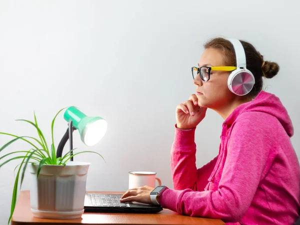 Kulaklık takan, evden çalışan, uzaktan eğitim yapan bir kadın. Kahve içen güzel kız internette video konferansı dinliyor. Masada gözlüklü bir iş kadını.