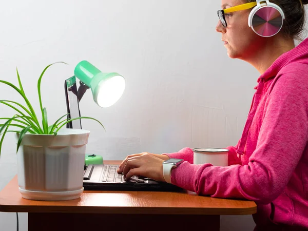 Kulaklık takan, evden çalışan, uzaktan eğitim yapan bir kadın. Kahve içen güzel kız internette video konferansı dinliyor. Masada gözlüklü bir iş kadını.