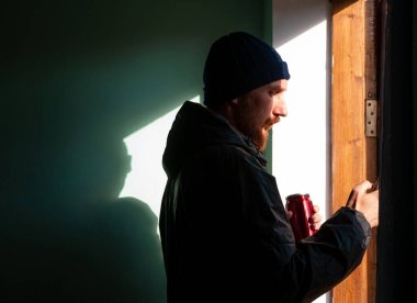 Sakallı, siyah yağmurluk giymiş, elinde akıllı telefonuyla duvara sert gölgeyle mesaj atan bin yıllık bir adam. Otantik erkek gezgin blogcu adam yaşam tarzı Solo seyahat macerası. Günlük iletişimi