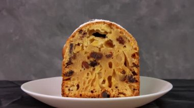 Noel meyveli kekin üzerine koyu arkaplan üzerine pudra şekeri döküldü. Şenlikli pasta pişirme. Çalıntı hamur tarifi malzemeleri fındıklar kurutulmuş şekerli meyve yumurtası kepekli un kurutulmuş meyve yağı. Yeni yıl dekorasyon masası servisi.