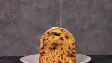 Noel meyveli kekin üzerine koyu arkaplan üzerine pudra şekeri döküldü. Şenlikli pasta pişirme. Çalıntı hamur tarifi malzemeleri fındıklar kurutulmuş şekerli meyve yumurtası kepekli un kurutulmuş meyve yağı. Yeni yıl dekorasyon masası servisi.