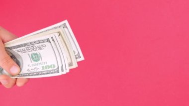 El, Amerikan Doları 'nı tutuyor. Para, pembe renkli arka plan. 100 Amerikan Doları 'nı sayıyorum. Amerikan para birimini tasarruf etmek, zenginlik kavramı. Çevrimiçi kumarhane kazananı başarılı ticaret