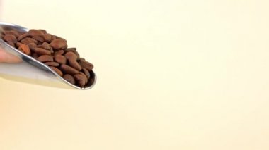 Kafe 4K 'ye çelik kepçeden kahve çekirdekleri dökülüyor. Kahve dükkanında poşetlere doldurulmuş taze kavrulmuş aromatik taneler. Sıcak kahvaltı espresso kapuçino indirimi. Düşen tohumlar yakın plan.