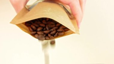 Kafe 4K 'ye kese kağıdından kahve çekirdekleri dökülüyor. Kahve dükkanını dolduran taze kavrulmuş aromatik taneler. Sıcak kahvaltı espresso kapuçino indirimi. Düşen tohumlarla birlikte paketle.