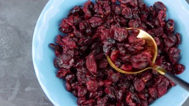 Kurutulmuş yaban mersinli mavi kase elinde. Sağlıklı kuru kırmızı böğürtlen. Organik besleyici, lezzetli çiftçiler, C vitamini. Doğal besin malzemeleri, kahvaltı lapası, tahıl gevreği..