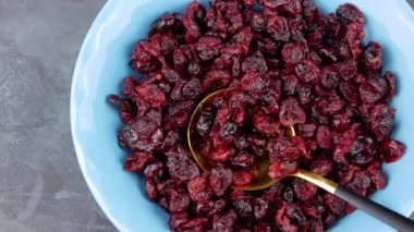 Kurutulmuş yaban mersinli mavi kase elinde. Sağlıklı kuru kırmızı böğürtlen. Organik besleyici, lezzetli çiftçiler, C vitamini. Doğal besin malzemeleri, kahvaltı lapası, tahıl gevreği..