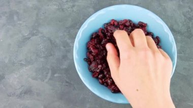 Kurutulmuş yaban mersinli mavi kase elinde. Sağlıklı kuru kırmızı böğürtlen. Organik besleyici, lezzetli çiftçiler, C vitamini. Doğal besin malzemeleri, kahvaltı lapası, tahıl gevreği..