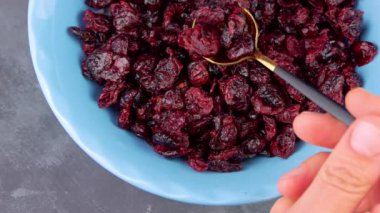 Mavi kâse üst manzaralı kurumuş kızılcık. Sağlıklı kuru kırmızı çilek kaşığı. Organik besleyici, lezzetli çiftçiler, C vitamini. Doğal besin malzemeleri, kahvaltı lapası, tahıl gevreği.