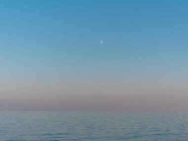 Mor gün batımında mavi denizi ve ayı olan boş bir sahil. Güney manzaralı akşam duvar kâğıdı, yaz tatili sezonluk arka plan. Canlı mavi dalgalar kopyalama alanını bulanıklaştırdı. Tatil köyü reklamı.