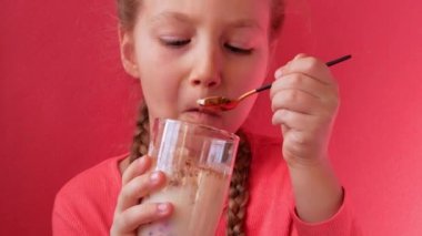 Yoğurt yiyen pembe arka plan. Süt ürünleri diyeti Lactobacillus Acidophilus, ev yapımı sağlıklı kahvaltı menüsü. Çocuk sağlık hizmetleri. Vejetaryen fındık sütlü jelatin sütsüz tatlı Protein pudingi.