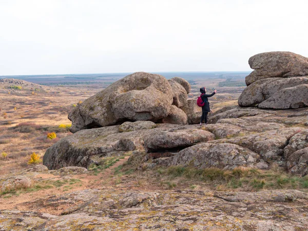 Dağ zirvesinde akıllı telefon ve sırt çantalı bir gezgin kadın. Manzaralı manzaranın fotoğrafını çeken bir kız. Aktif Yaşam Tarzı Turizmi. Solo gezintisi aşırı doğa aktivitesi