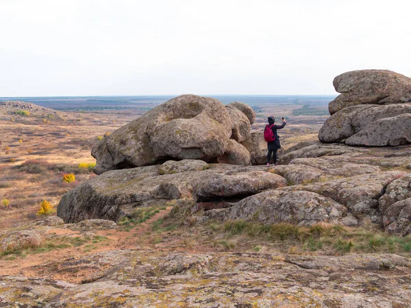 Dağ zirvesinde akıllı telefon ve sırt çantalı bir gezgin kadın. Manzaralı manzaranın fotoğrafını çeken bir kız. Aktif Yaşam Tarzı Turizmi. Solo gezintisi aşırı doğa aktivitesi