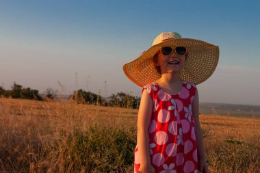 Hasır şapkalı, elinde buğday tarlasında dikenleri olan pembe yazlık elbisesi olan sevimli küçük kız. Gün batımında kırsal alanda güneş gözlüklü, gülümseyen uzun sarı saçlı çocuk. Aile tarım tarım kavramı