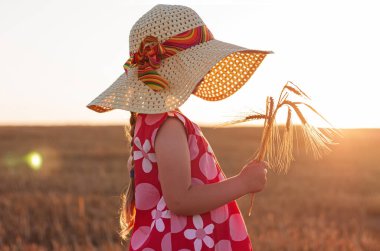 Hasır şapkalı, elinde buğday tarlası manzaralı sivri uçlu pembe yazlık elbisesi olan sevimli küçük kız. Gün batımında kırsal alanda uzun sarı saçlı bir çocuk. Aile tarım tarım kavramı