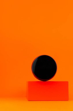 Kozmetik tonal fondöten, geometrik podyum turuncu arka planda siyah kavanoz modeli. Makyaj malzemesi dengeleniyor. Yumuşak BB sıvı krem yüz derisi. Skintone düzeltme Modern asgari sunum içeriği