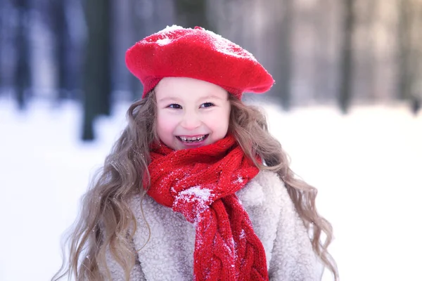 Portrait of cute beautiful pretty girl kid, happy cheerful positive lovely child is smiling walking in snowy park at winter cold frosty day with snow laughing having fun in warm clothes hat and gloves — Zdjęcie stockowe