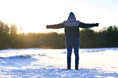 Photo of unrecognisable guy walking in warm clothes hat coat at winter cold frosty day outdoors open spread his hands wide. Freedom happiness concept. Back view.