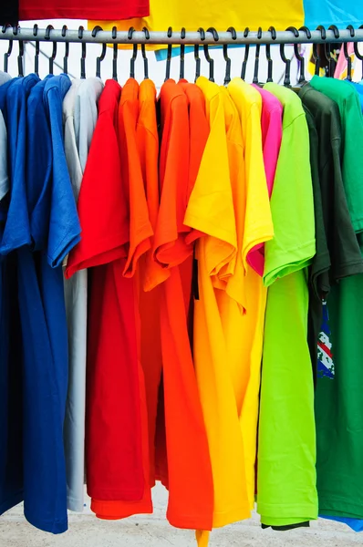 T-shirt colorida com cabides no mercado — Fotografia de Stock