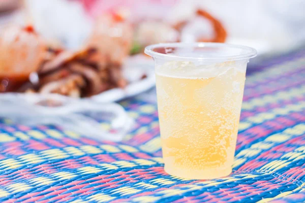 Bier mit Eis in Plastikglas und dof Essen Hintergrund. — Stockfoto