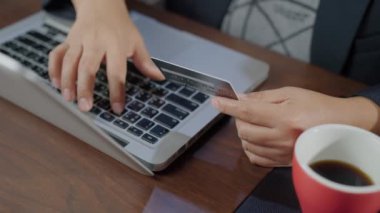 SLOW MOTION of Hand typing the keyboard and shopping online while holding credit card. Cardholder holding credit card making e bank online payment. Paying for purchase in web store using laptop