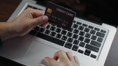 B rulo Yavaş El Hareketi klavyeyi yazıp kredi kartı tutarken internetten alışveriş yapıyor. Kredi kartı sahibi bankaya online ödeme yapıyormuş. Bilgisayarla web mağazasında satın almak için ödeme