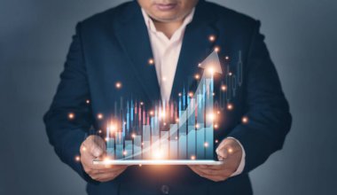 İşadamı, işinde olumlu göstergelerin artması planıyla tableti elinde tutuyor. İş planlama, başarıya giden grafikler. Borsa değeri. Fırsat. Dijital pazarlama.